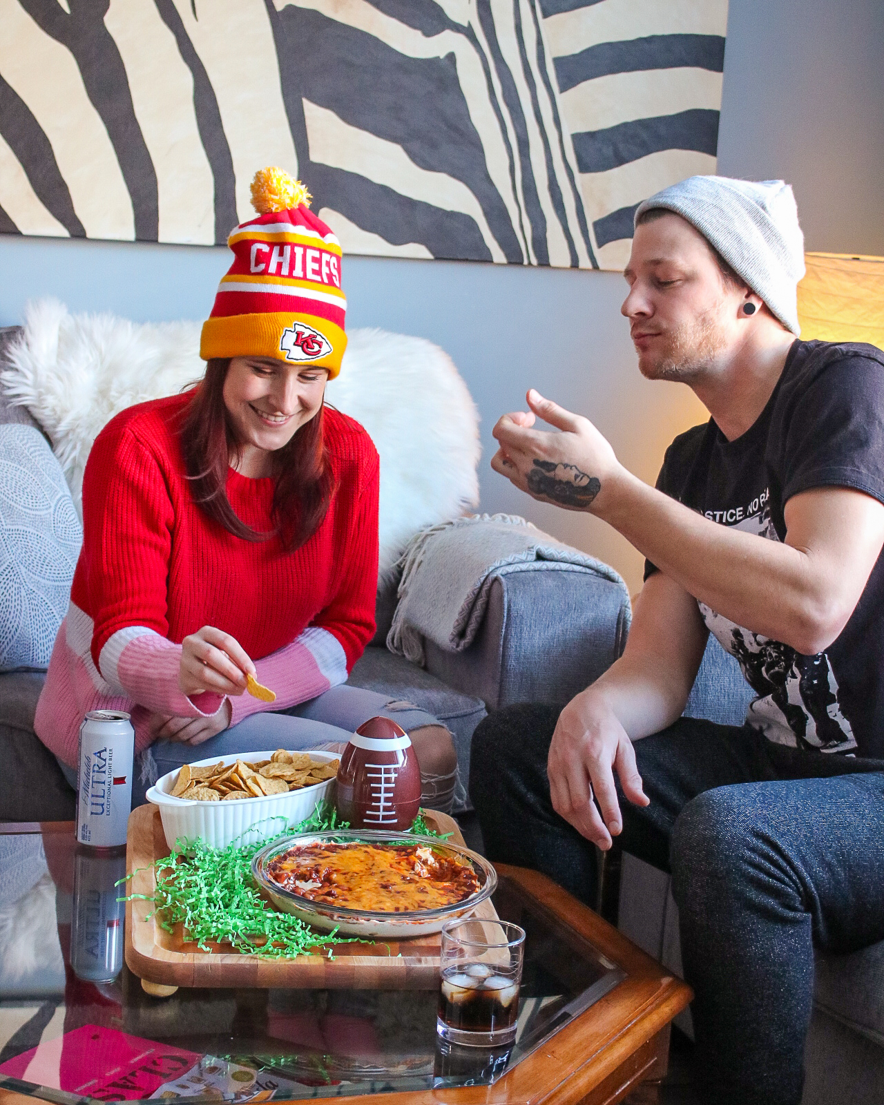 easy cheesy chili dip - couple sitting on coach enjoying dip while watching a football game