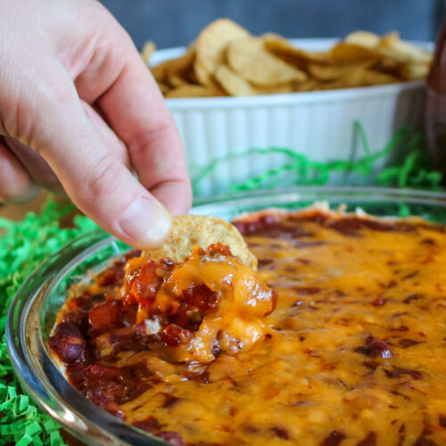 man dipping tortilla chip in easy cheesy chili dip