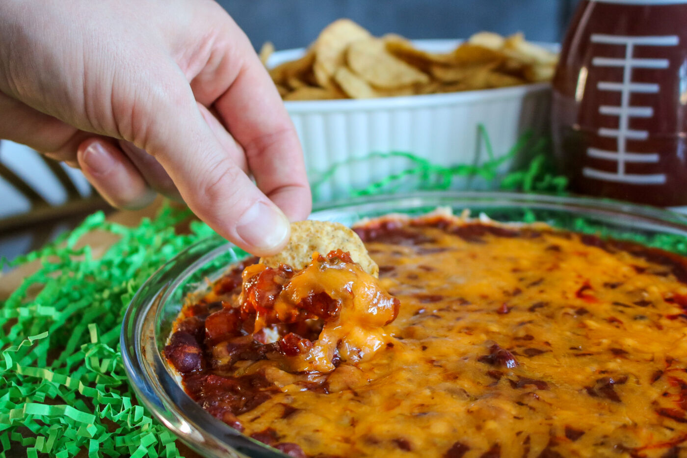 man dipping tortilla chip in easy cheesy chili dip