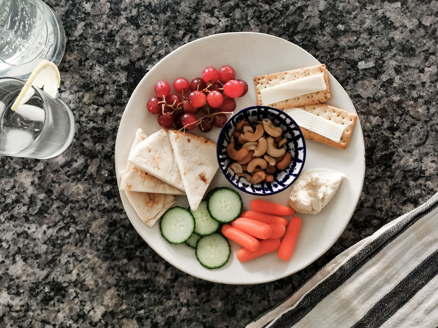 grazing lunch plate with vegetables, hummus, grapes, cheese and crackers
